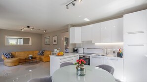 A modern kitchen with white cabinets, a dining area with a glass table, and a living room with a yellow sofa. - Close to the beach, quiet location, family-friendly (Funtana)