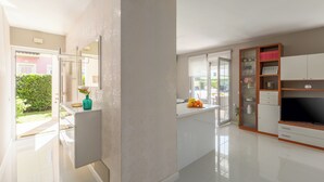 A modern living room with a flat-screen TV, a glass-fronted cabinet, and a sliding glass door leading to a balcony. - Close to the beach, quiet location, family-friendly (Funtana)
