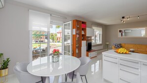 A modern kitchen with white cabinets, a dining area with a round table and chairs, and a view of the outdoors through large windows. - Close to the beach, quiet location, family-friendly (Funtana)