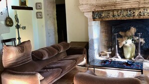 Un salon chaleureux avec une cheminée, un escalier en bois et un canapé.