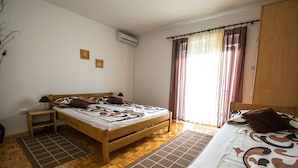 A bedroom with a wooden bed, a nightstand, a window with curtains, and a wooden wardrobe. - Apartment near the beach with free wifi and air conditioning (Starigrad Paklenica)