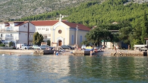 A coastal building with a red-tiled roof, a bell tower, and a stone wall in front. - Apartment near the beach with free wifi and air conditioning (Starigrad Paklenica)
