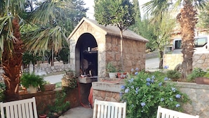 A stone structure with an arched entrance, surrounded by potted plants and a table with chairs. - Apartment near the beach with free wifi and air conditioning (Starigrad Paklenica)