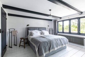Un dormitorio con cama, radiador, ventana y puerta.