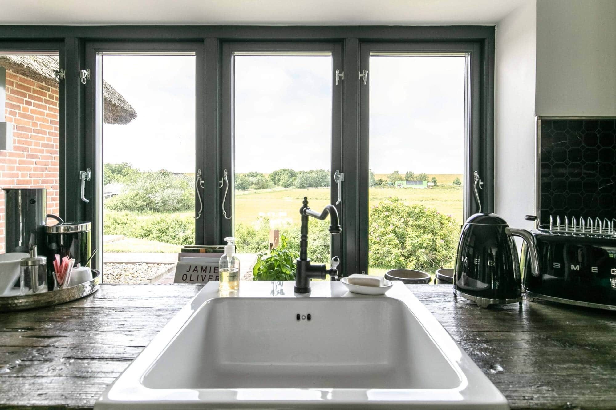 A kitchen with a large window, a sink, and a coffee maker.