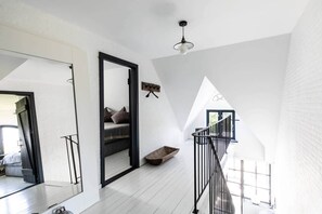 Un dormitorio tipo loft moderno con un espejo grande, un banco de madera y una escalera.