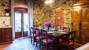 Un comedor con pared de piedra, mobiliario de madera y vistas a través de una puerta.