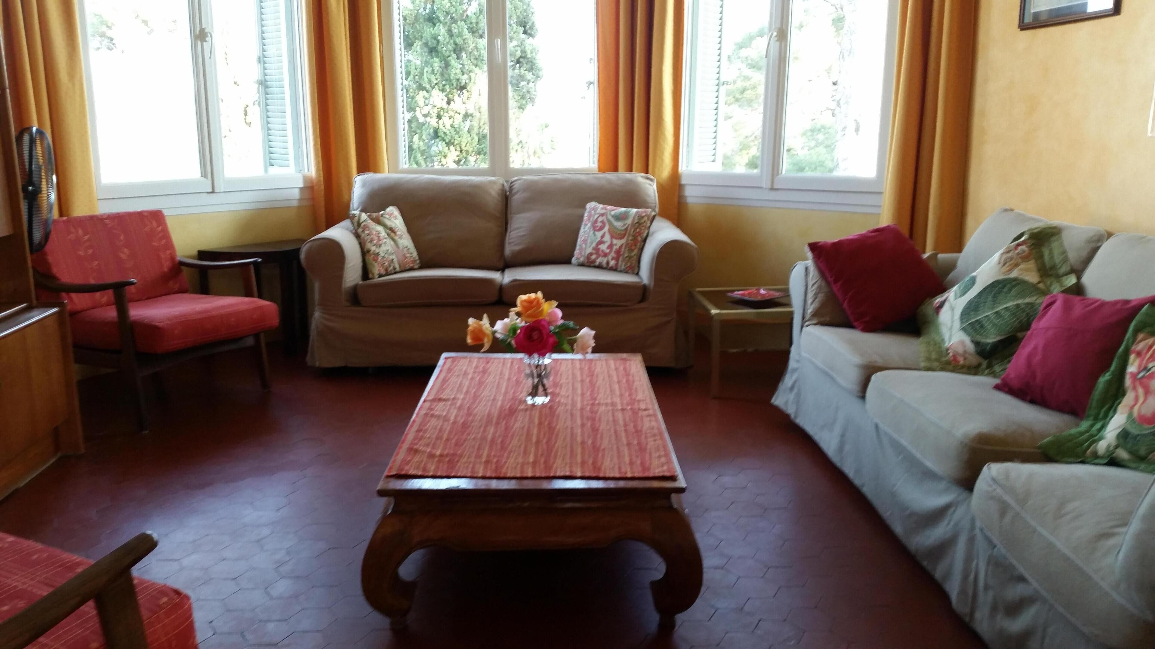 A living room with a sofa, chairs, a coffee table, and a window with curtains.
