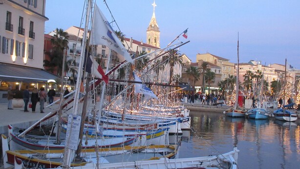 A marina with boats docked, a prominent building with a clock tower in the background, and a crowd of people on the promenade. - House / Villa - SANARY SUR MERHouse with character (Sanary-Sur-Mer)