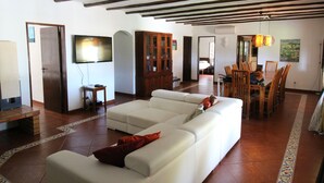 A spacious living room with a large white sectional sofa, a wooden cabinet, and a dining area with a table and chairs. - Beautiful 10 people villa with pool on one of the most beautiful places in Albufeira (Albufeira)