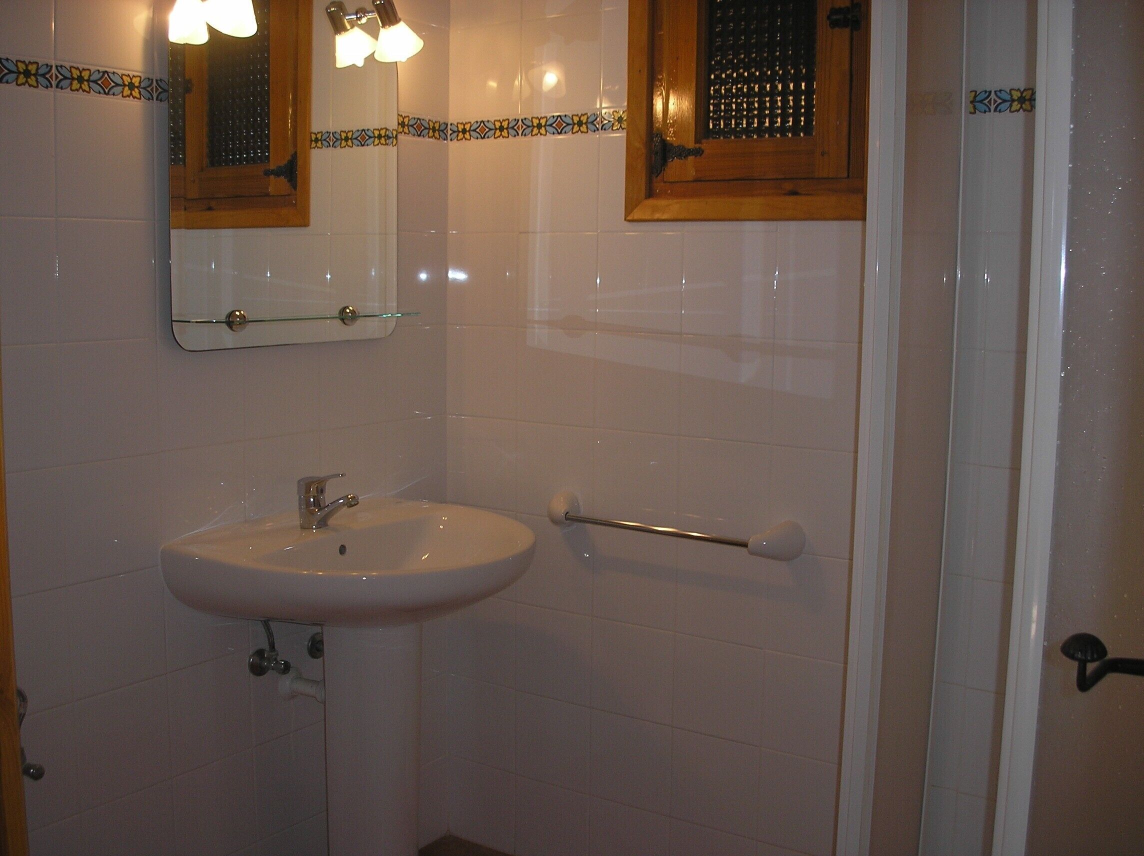 A bathroom with a white sink, a mirror, and a window with a wooden frame.