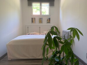A bedroom with a bed, a window, and a potted plant. - Apartment I" between Bordeaux and the Atlantic "Mimosa" (Brach)