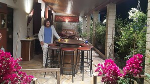 An outdoor patio with a round table and bar stools, surrounded by potted plants and flowers. - Apartment I" between Bordeaux and the Atlantic "Mimosa" (Brach)