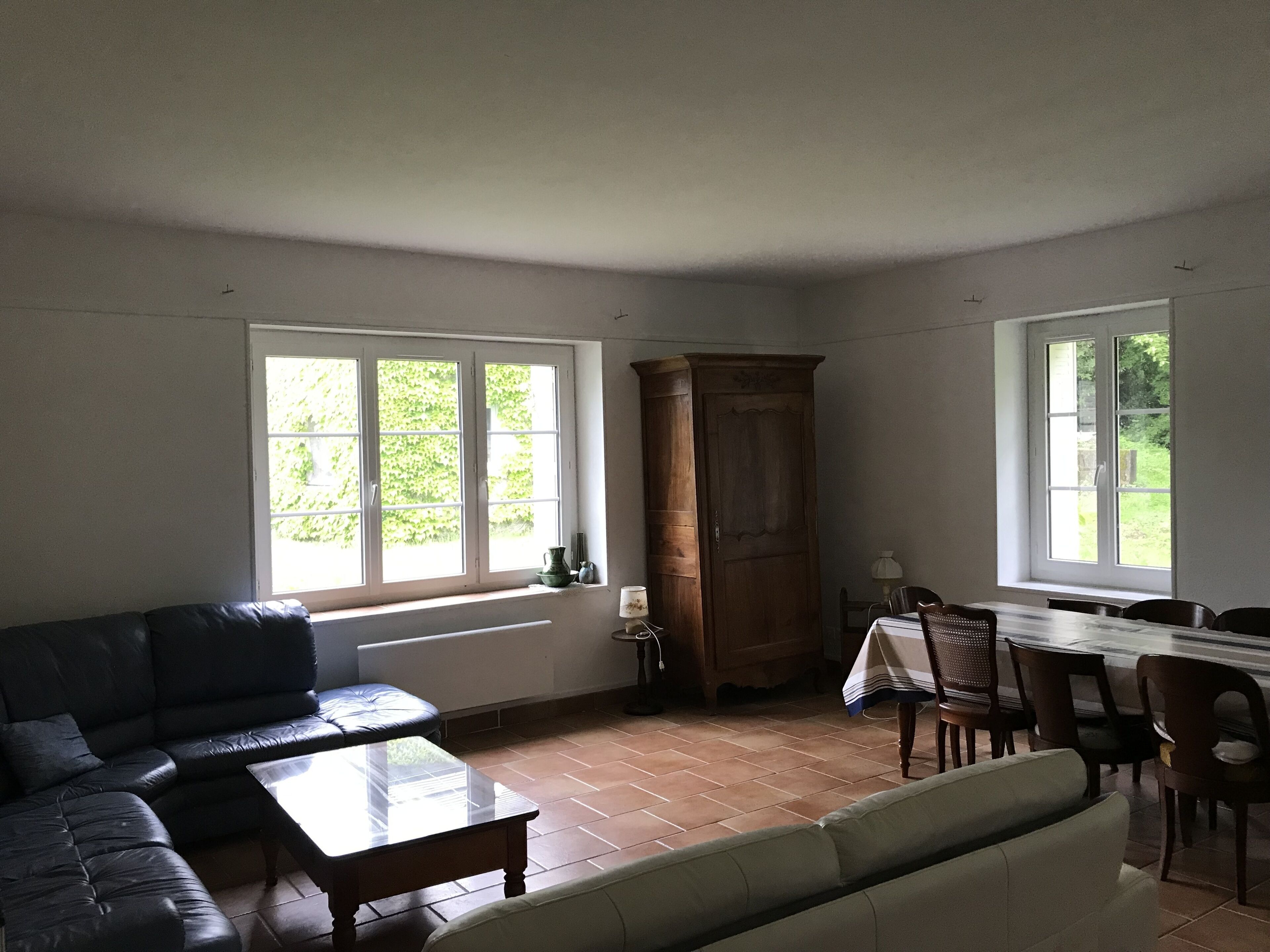 Amplia sala de estar con un sofá, una mesa de centro, un aparador y una zona de comedor con sillas y una mesa.