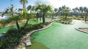 A golf course with a green artificial turf, palm trees, and a pool in the background. - Perfect Home for your Vacation SL4807 (Kissimmee)