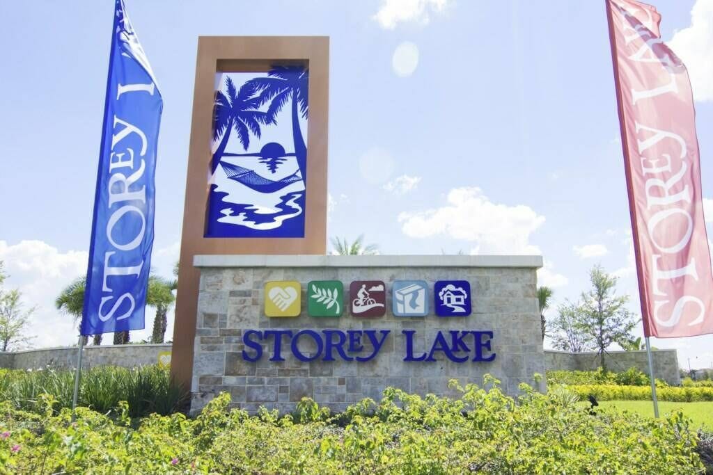 Señal de Storey Lake con palmeras y una playa, rodeada de follaje y dos banderas.
