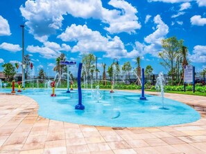 A water fountain area with multiple jets, surrounded by a tiled walkway and palm trees. - Perfect Home for your Vacation SL4807 (Kissimmee)