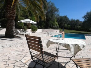 Ein Poolbereich mit einer Holzbank, einem Tisch mit weißer Tischdecke und einem Pool.
