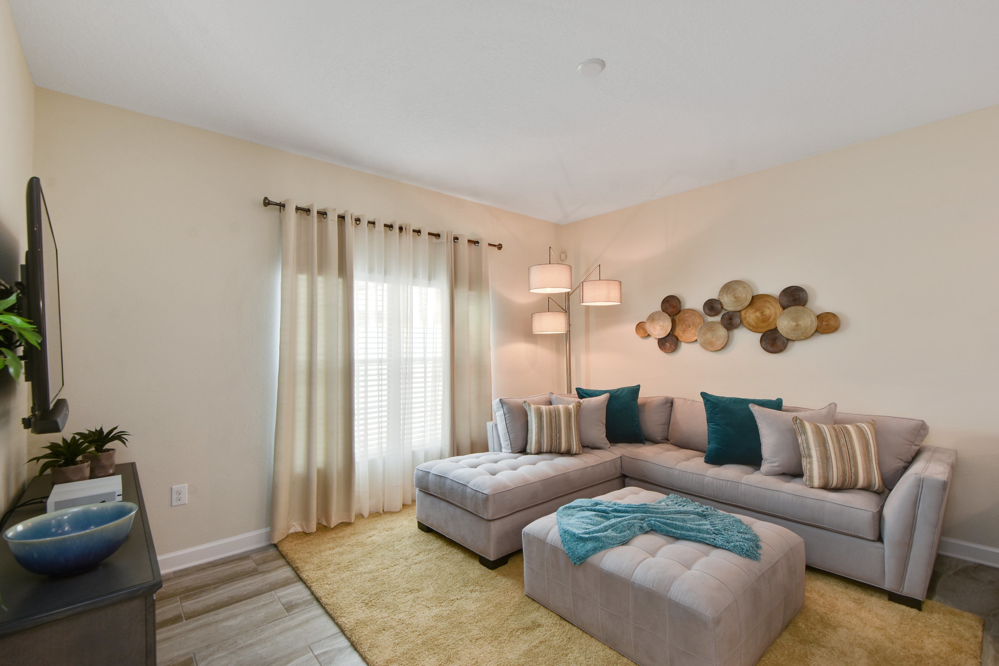 A living room with a sectional sofa, ottoman, and a large floor lamp.