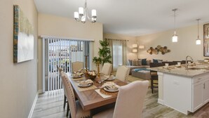 A modern kitchen with a central island, white cabinetry, and pendant lighting. - Charming Vacation Townhome with Pool CG1576 (Davenport)