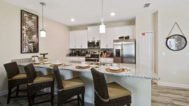 A modern kitchen with a central island, white cabinets, stainless steel appliances, and a clock on the wall. - Charming Vacation Townhome with Pool CG1576 (Davenport)