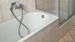 Un baño con bañera, ducha y paredes de azulejos.
