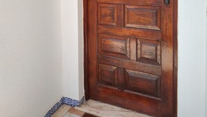 A wooden door with a brass knocker and a small mailbox on the wall.