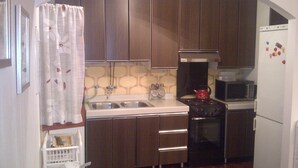 Una cocina compacta con lavamanos, estufa, microondas y refrigerador.