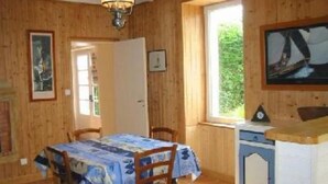 Ein Zimmer aus Holz mit einem Esstisch, Stühlen, einem Fenster und einem Wandbild.