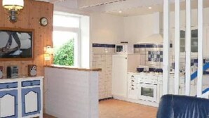 Ein Zimmer mit Holzboden, einem weißen Schrank mit blauen Akzenten, einer Uhr und einem Fenster mit Blick auf Grünflächen.