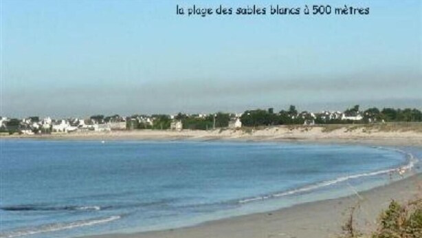 Ein Strand mit freiem Blick auf das Meer und einer entfernten Küstenlinie mit Gebäuden.