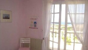 Ein Zimmer mit einem Bett, einem Sessel und einem Fenster mit Vorhängen.