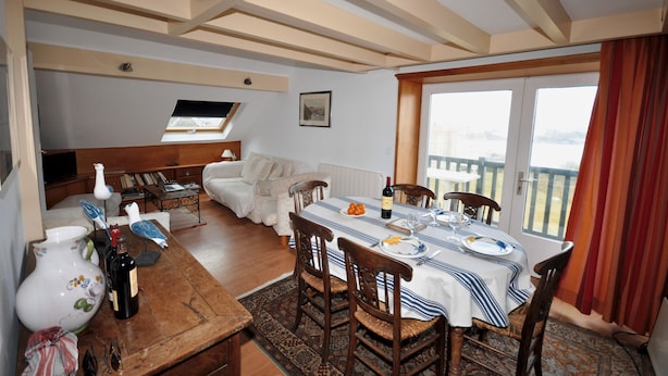 A dining area with a table set for four, a sofa, and a view of the outdoors.