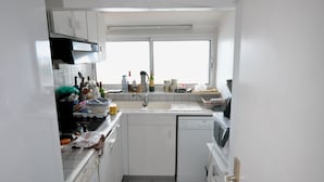 A compact kitchen with white cabinets, a washing machine, a microwave, and a sink.