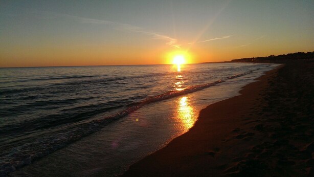 A beach at sunset with the sun reflecting on the water. - House with private pool and wi. fi (Coma-Ruga)