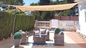 An outdoor patio with a wooden deck, wicker furniture, and a large umbrella. - House with private pool and wi. fi (Coma-Ruga)