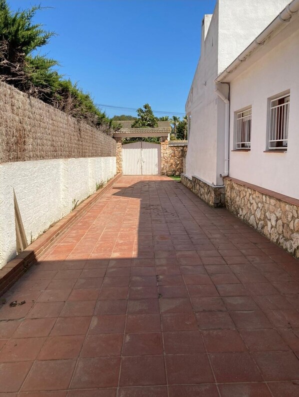 A paved courtyard with a stone wall on one side and a white building on the other.