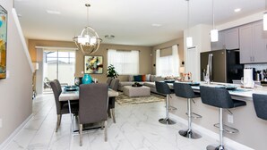 A modern kitchen with a refrigerator, stove, and bar area. There is a dining table with chairs and a sofa in the living area. - Dream Vacation Home Close to Disney SL4839 (Kissimmee)