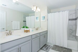 A modern bathroom with two sinks, a large mirror, and a shower area.