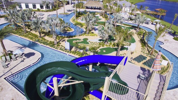 A water park with a large slide, pool areas, and surrounding palm trees.