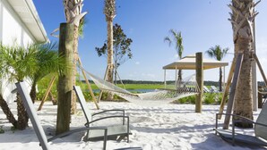 A beach area with hammocks, lounge chairs, and a gazebo overlooking a beach.