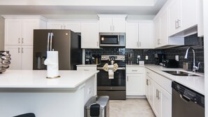 A modern kitchen with white cabinets, stainless steel appliances, and a tiled backsplash.