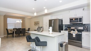 A modern kitchen with white cabinets, stainless steel appliances, and a central island with bar stools.