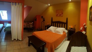 A bedroom with a bed, bedside table, lamp, and a view of another room.