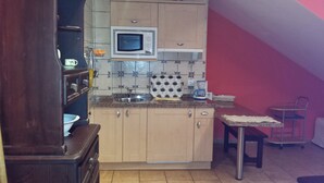 A compact kitchen with a microwave, sink, and a small dining area with a chair.