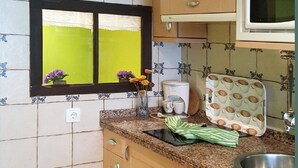 A kitchen with a window, a coffee maker, a microwave, and a sink.