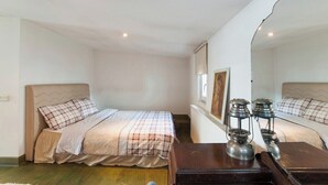 A bedroom with two beds, a wooden nightstand, and a mirror.