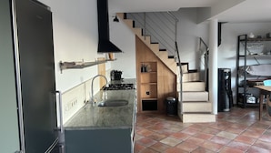 Une cuisine moderne équipée d’une cuisinière à gaz, d’un évier et d’un escalier menant à une mezzanine.