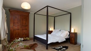 A four-poster bed with white linens, a wooden wardrobe, and a cowhide rug on a wooden floor. - Spacious and stylish in the monument to the Müritz, near the lake and golf course (Lexow)