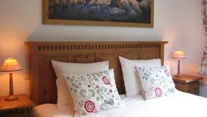 A bedroom with a wooden headboard, two bedside tables with lamps, and floral-patterned pillows. - Beautiful, spacious 12 person chalet, Portes du Soleil, France (Abondance)
